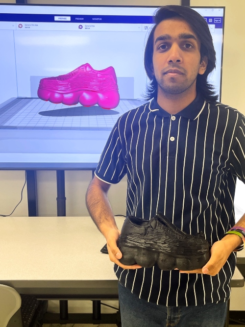 A student displays a 3D shoe design