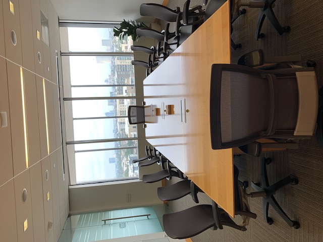 Photo of the meeting space layout for the Atlantic Room featuring a long table and chairs infront of a panaromic window view of the city